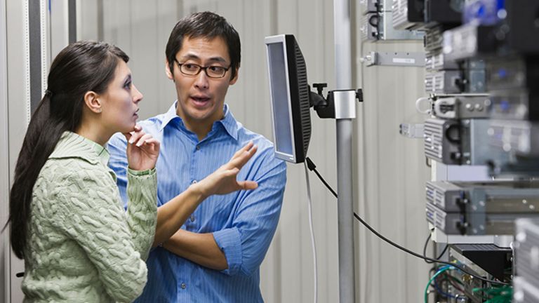 Two colleagues having a conversation in a server room.