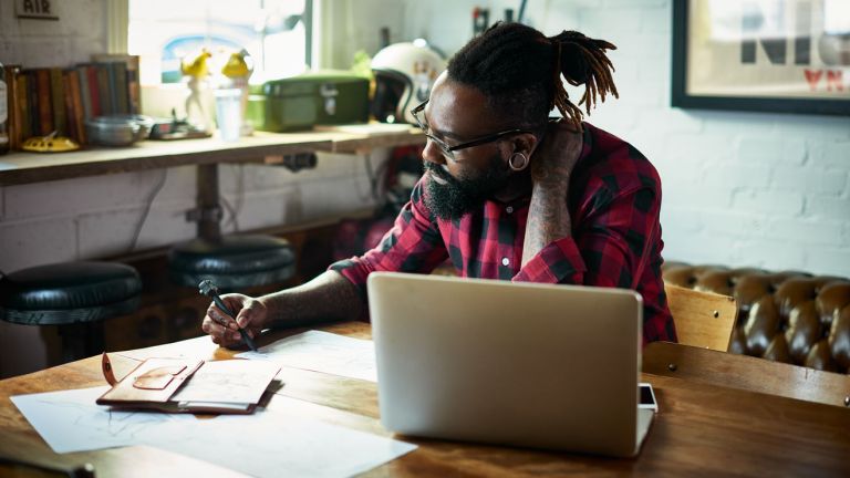 A man is writing with a laptop