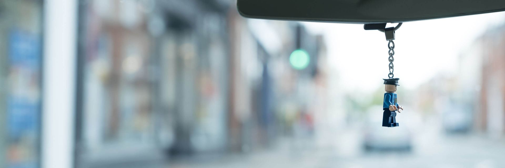 Keychain of a Lego policeman hanging from a car's rear view mirror