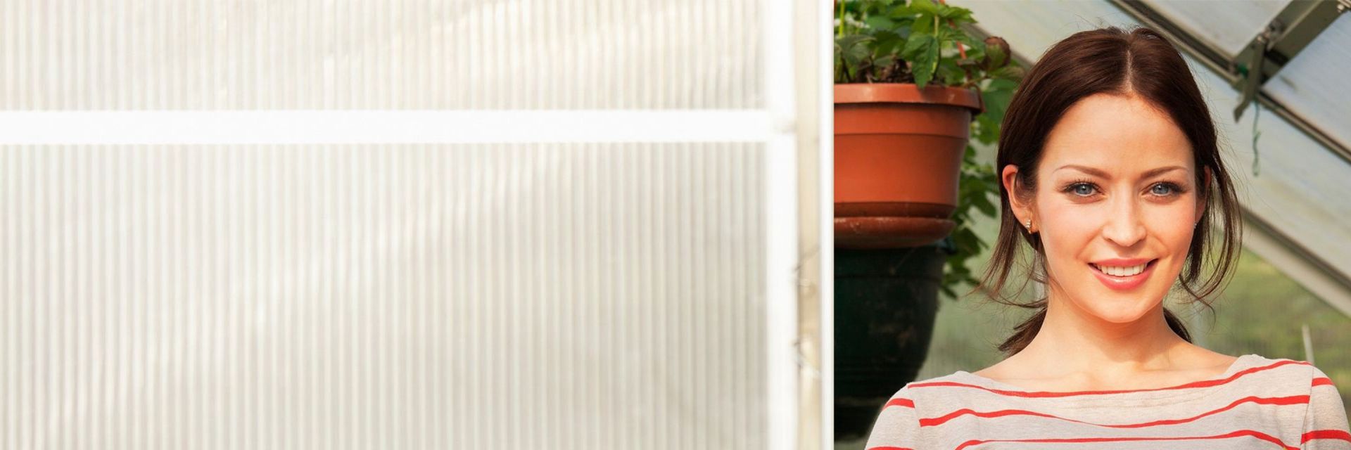  A woman standing in a greenhouse smiles at the camera