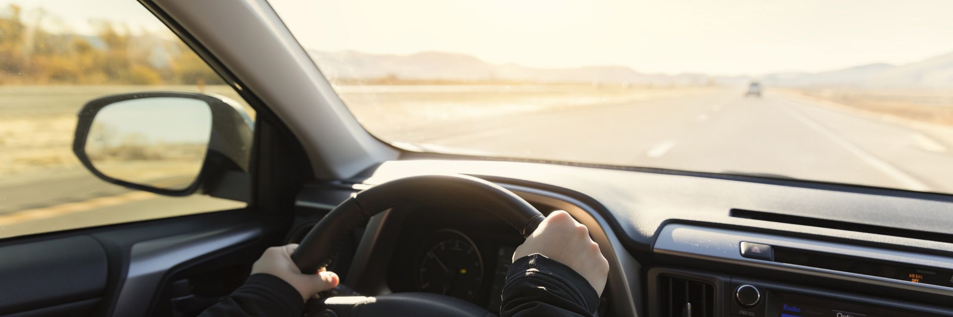 A man and a woman talk beside a car with the driver's door open
