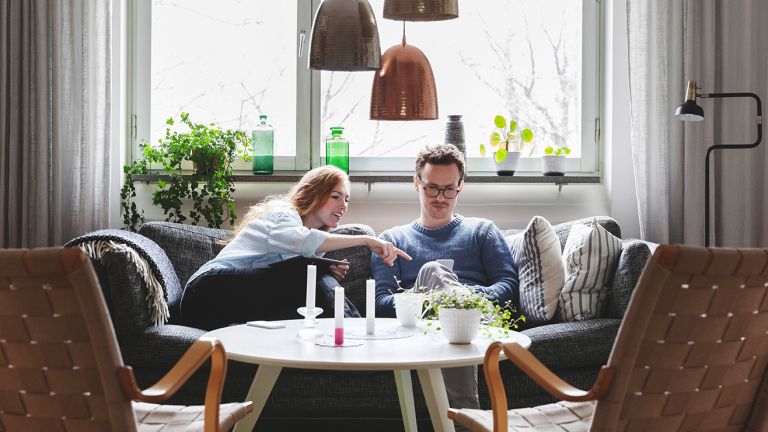  A man and a woman sitting in a living room looking at a phone together