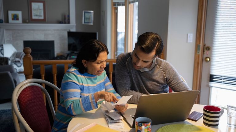 A couple are sat together working out bills with a laptop