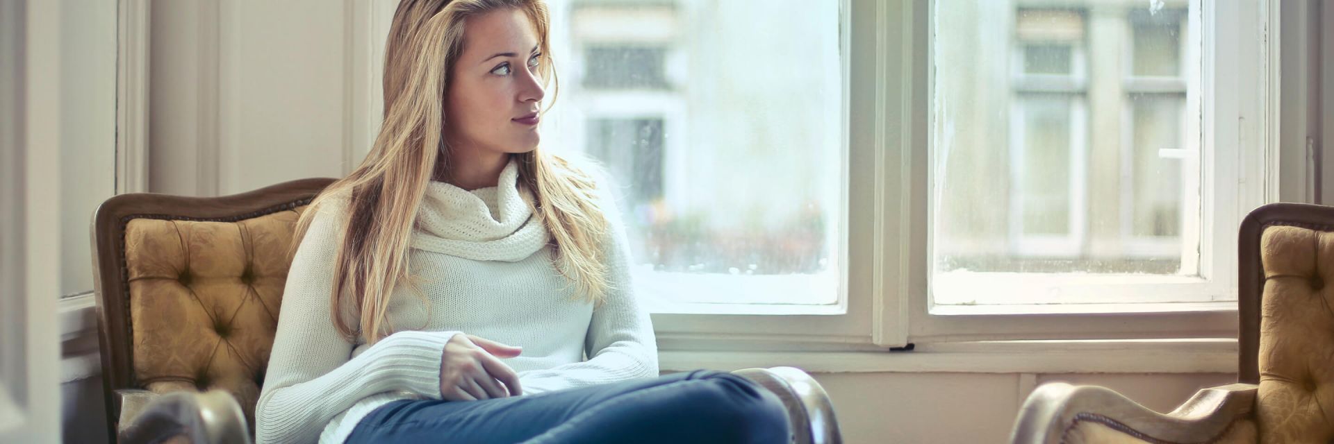  A woman curled up in an armchair by a window