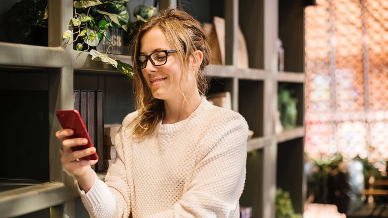  A woman standing outdoors looks at her phone