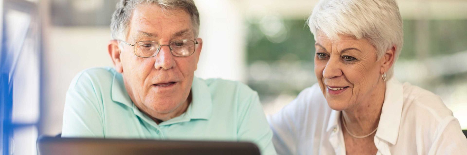 A man and a woman look at a laptop together.