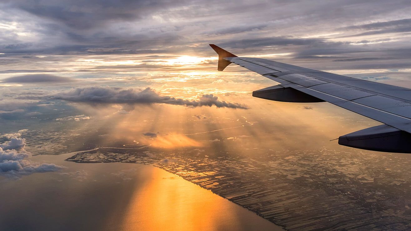  Sun rising in the sky behind the wing of a plane